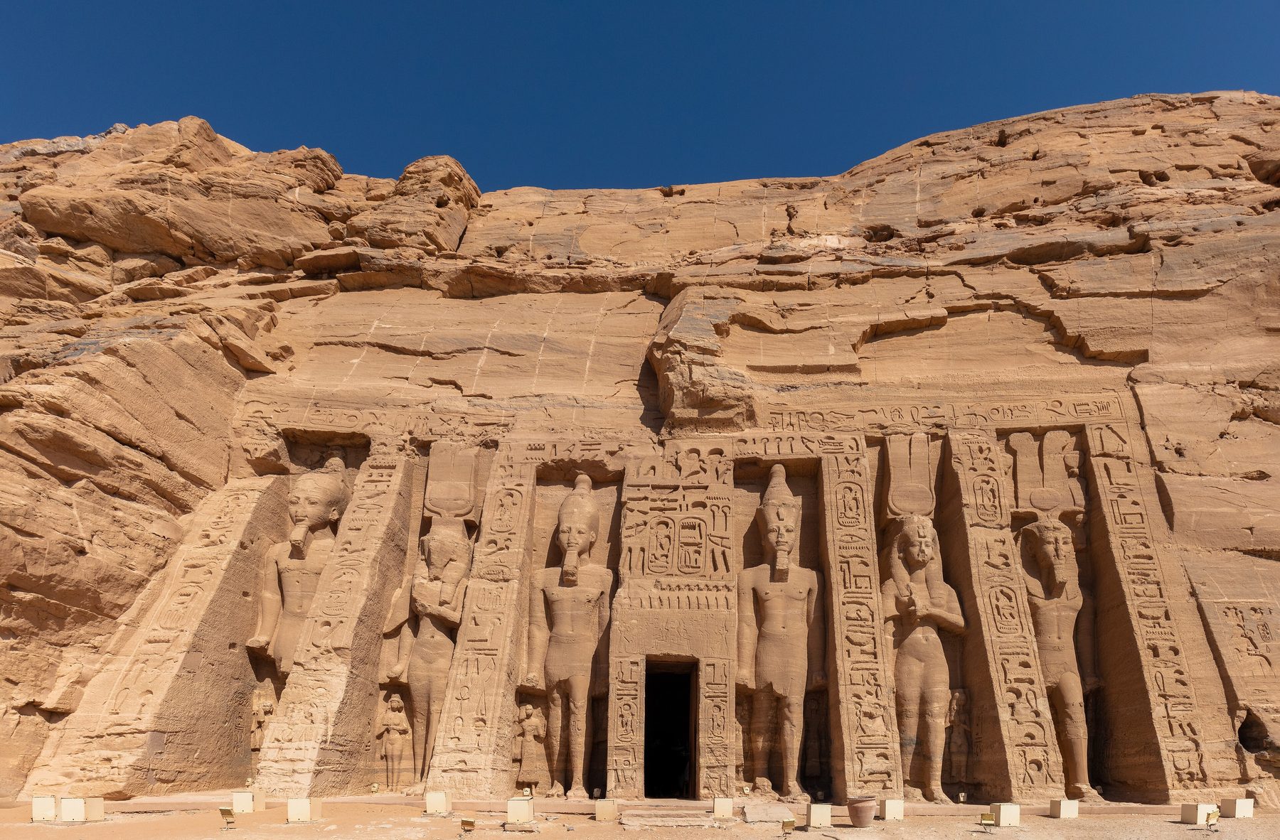 Photograph of the Small Temple of Abu Simbel showing colossal standing statues of Ramesses II and Queen Nefertari on the rock-cut façade.